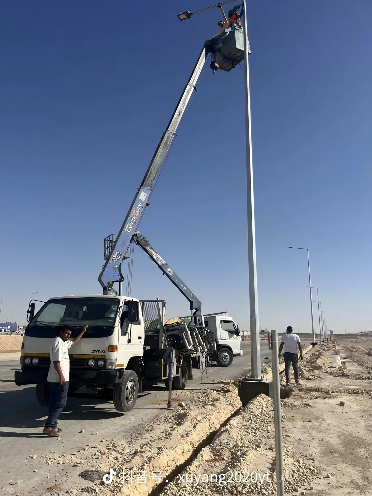 Crane-assisted installation of a road lighting pole